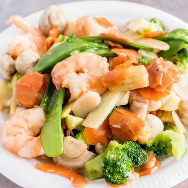 Stir-fried dish with shrimp, vegetables, and mushrooms on a white plate.