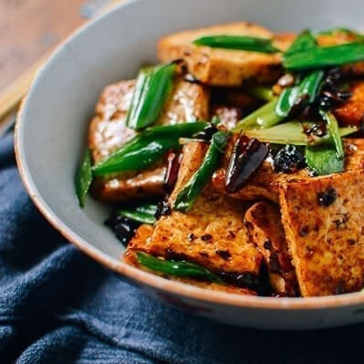 Bowl of tofu dish with green onions on a blue cloth